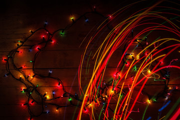 Colorful glowing garland on wooden background. Multicolored light lines.