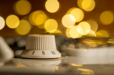 Macro of a white electric guitar volume knob on 9 with abstract bokeh lights in the background....