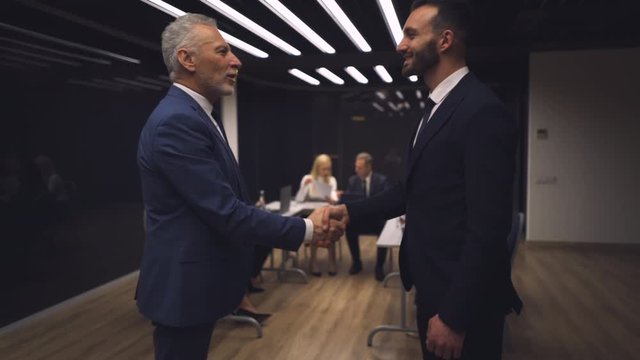 The business partners handshaking in the meeting room. slow motion