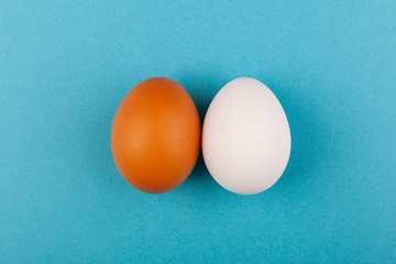 Two chicken eggs white and brown on a blue background. The concept of a healthy lifestyle, getting pure protein. Proper Breakfast.