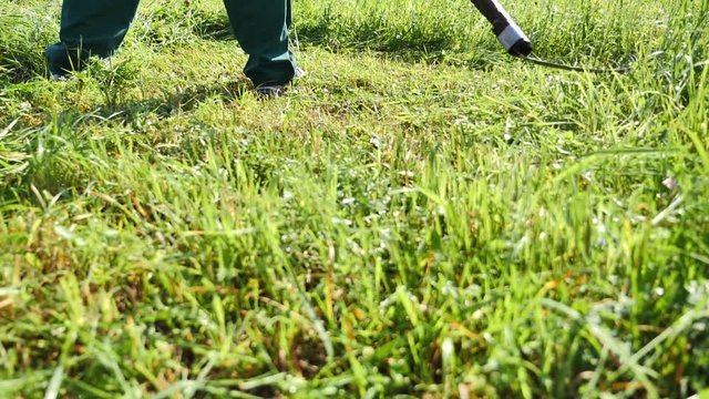 Slow motion footage of a farmer hand mowing the grass on a meadow with a scythe, the shot is moving