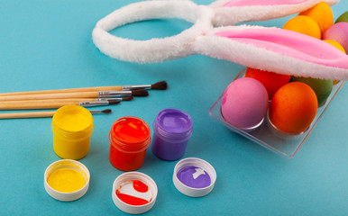 Colorful handmade Easter eggs, rabbit ears to play with, and jars of multicolored gouache with...