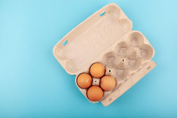 Egg Chicken eggs. Top view of an open gray box with brown eggs Isolated on a blue background. The concept of a healthy lifestyle, getting pure protein. Proper Breakfast. Four eggs.