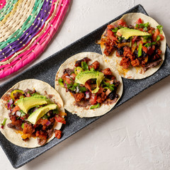 Mexican pork chorizo tacos with avocado and beans on white background