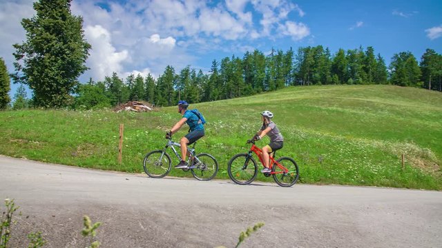 Couple riding  bike in the countryside, alluring view of lush green nature and churches in Lese, Slovenia