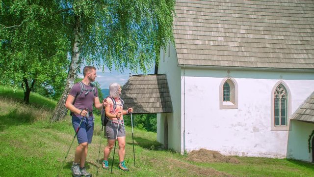 Dolly shot of a walking wanderer couple with hiking gear and backpack exploring surroundings of Lese, Slovenia.