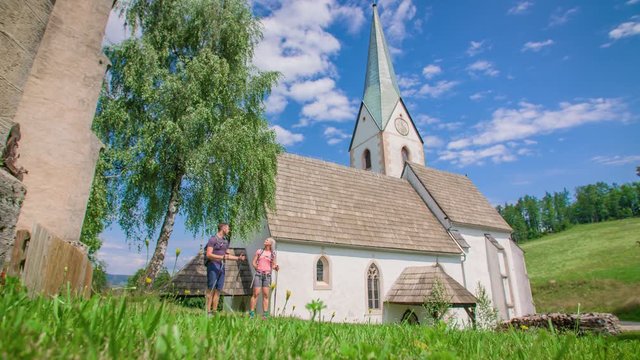 Panning shot of couples enjoying the amazing view of the old church architecture and surroundings.