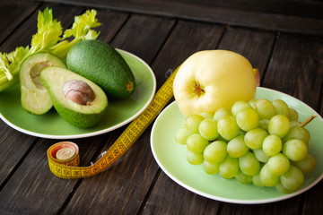 Workout and fitness dieting concept. Healthy lifestyle wth green color fruits and vegetables. With tape measure.