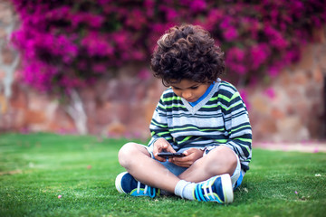 Kid boy playing with tablet outdoor. Children and gadget addiction concept