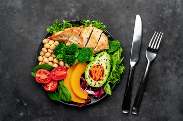 Bowl Buddha. chicken, broccoli, chickpeas, pumpkin, avocado, carrot, tomato on   a stone background