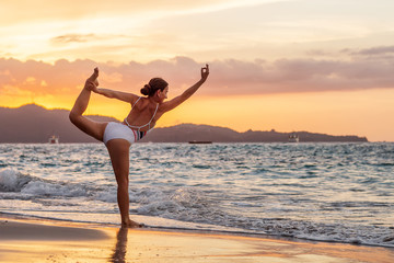 Fototapeta na wymiar Woman practices yoga at seashore