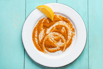 Mexican chili powder and orange slice on turquoise background