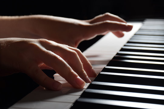 A child's hands play piano in this close up photo