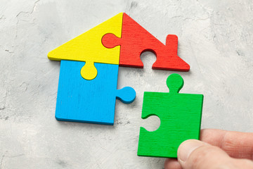 House puzzle Home loan. Parts of the house are brought together. Male hand holding puzzle piece