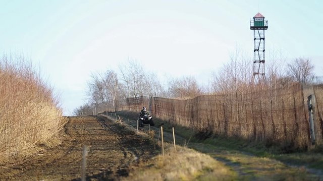 Border guards on ATV make inspection border in the winter season. The border area between Ukraine and Poland. Two border guards ATV. State border with a fence and plowed land.