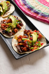 Mexican pork chorizo tacos with avocado and beans on white background