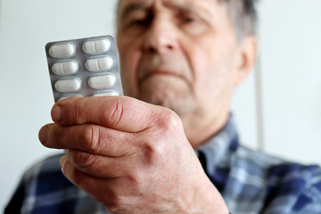 Elderly man with white pills in blister packs. Concept of medical prescription, cold treatment,...