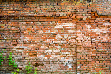 Old ruined brick wall with some concrete and cracks. Damaged antique brick wall