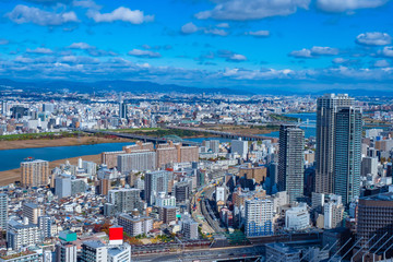 Japan. Panorama of Osaka from a height. Japanese urban landscape. Bridges over the Yodo river. Road and railway bridge. Big city under the sky with clouds. Osaka against the mountains. Town houses.