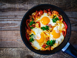 Shakshuka - fried eggs with vegetables in frying pan