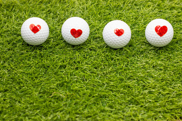 Naklejka premium Golf ball with red heart on golf ball on green grass background