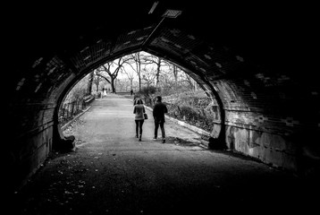 Silllhouette Couple Walking Udner Bridge through Central Park New York