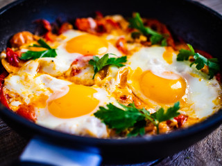 Shakshuka - fried eggs with vegetables in frying pan