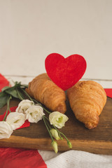 Croissants and white flowers with hearts on a wooden board. Valentine's day background concept.