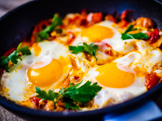 Shakshuka - fried eggs with vegetables in frying pan
