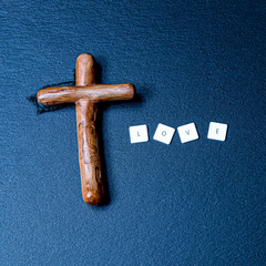 Wooden Christian cross on a dark background with the inscription love.