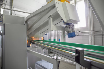 Machine for blowing plastic bottles from PET preforms, industrial conveyor belt in factory interior.
