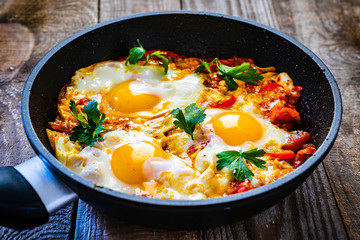 Shakshuka - fried eggs with vegetables in frying pan