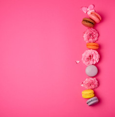 sweet multi-colored macarons with cream and a pink rose bud