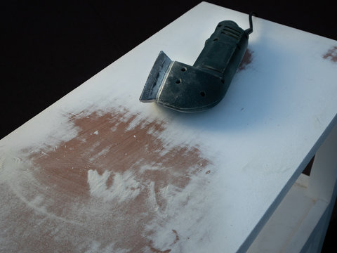 triangular sander flap on a table full of dust with a black background