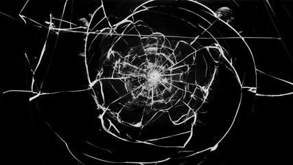 Round white cracks in glass on black background.