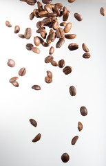 Falling coffee beans, in motion, on a white background. Selective focus.