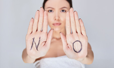 Close-up, a young girl with the inscription NO on her palms.