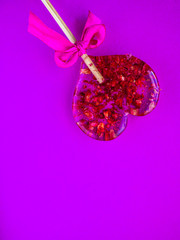 Red heart-shaped lollypop shot over purple background, minimalist concept for Valentines Day, Mothers Day. Love creative hearts shape, minimal simple design for wedding, anniversary invitations