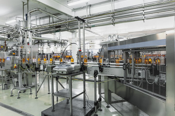 Industrial interior of natural juice plant production. Conveyor belt, filled bottles on beverage factory, industry production line.
