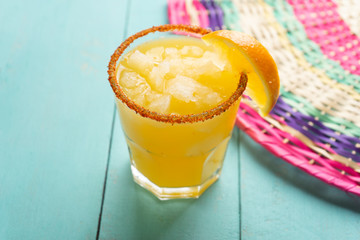 Mexican orange margarita cocktail with chili powder on turquoise background