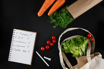 Fresh vegetables and a shopping list on a black background. Carrots, tomatoes, dill, lettuce and...