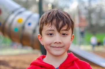 Portrait of a young, happy, smiling boy in a children's playground.