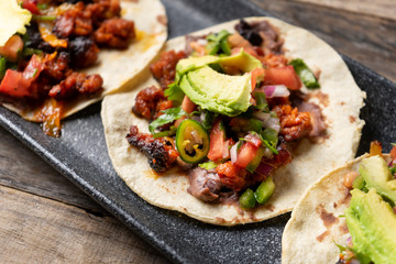 Mexican pork chorizo tacos with avocado and beans on wooden background