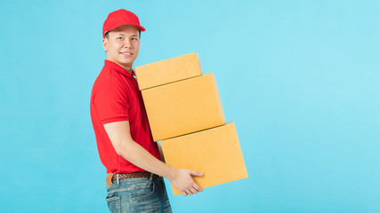 Asian happy delivery man carrying paper parcel boxes isolated on blue colour background.Concept of...