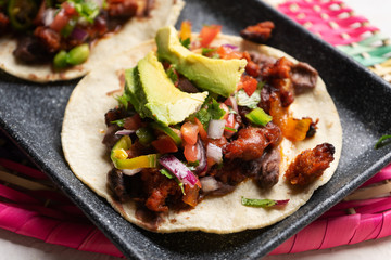Mexican pork chorizo tacos with avocado and beans on white background
