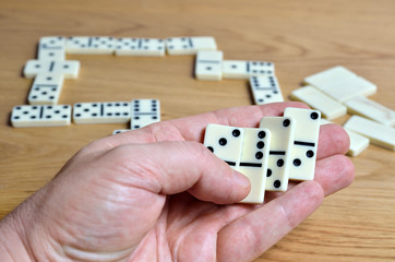 Playing dominoes on a wooden table. Dominoes game concept.