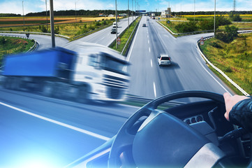 Fototapeta premium Abstract background with a truck in motion, truck steering wheel and a road with cars and a sky with blue lights