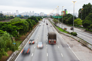 Beginning of the day in metropolis, bright lights and vehicles in transit. Sao Paulo city highway beside the river. Skyline, cars and traffic on the road at high speed. Marginal Tiete Highway