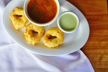 A plate with three Medu Vada donut fritters at an Indian restaurant