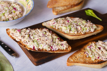 Tuna salad sandwiches on chopping board, white background. Horizontal image